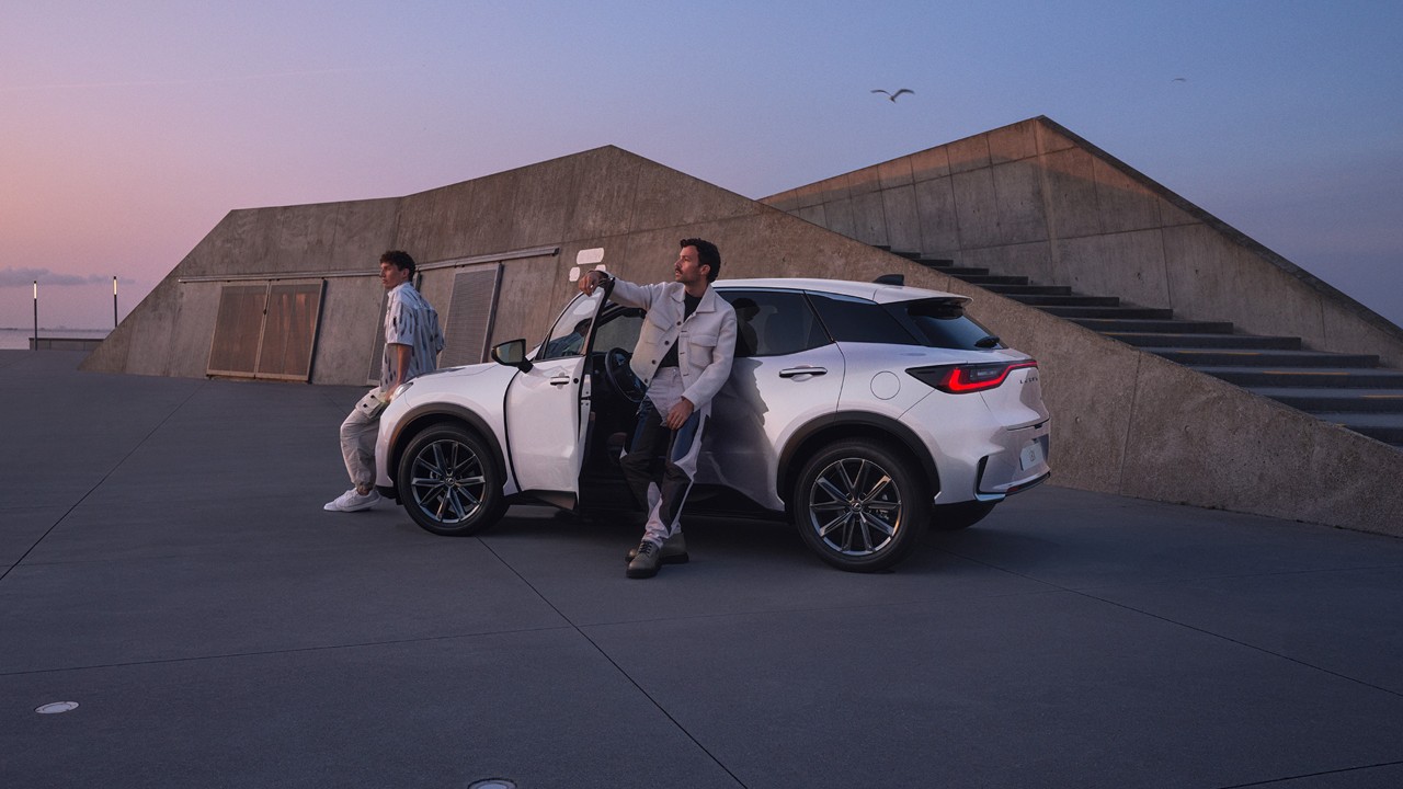 Two people stood next to a parked Lexus LBX