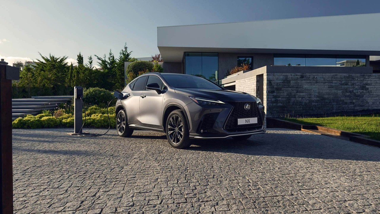 A Lexus NX plugged into a charger outside a home